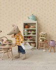 Two toy mice having a tea party in a miniature room with a shelf of tea sets. Dad Mouse