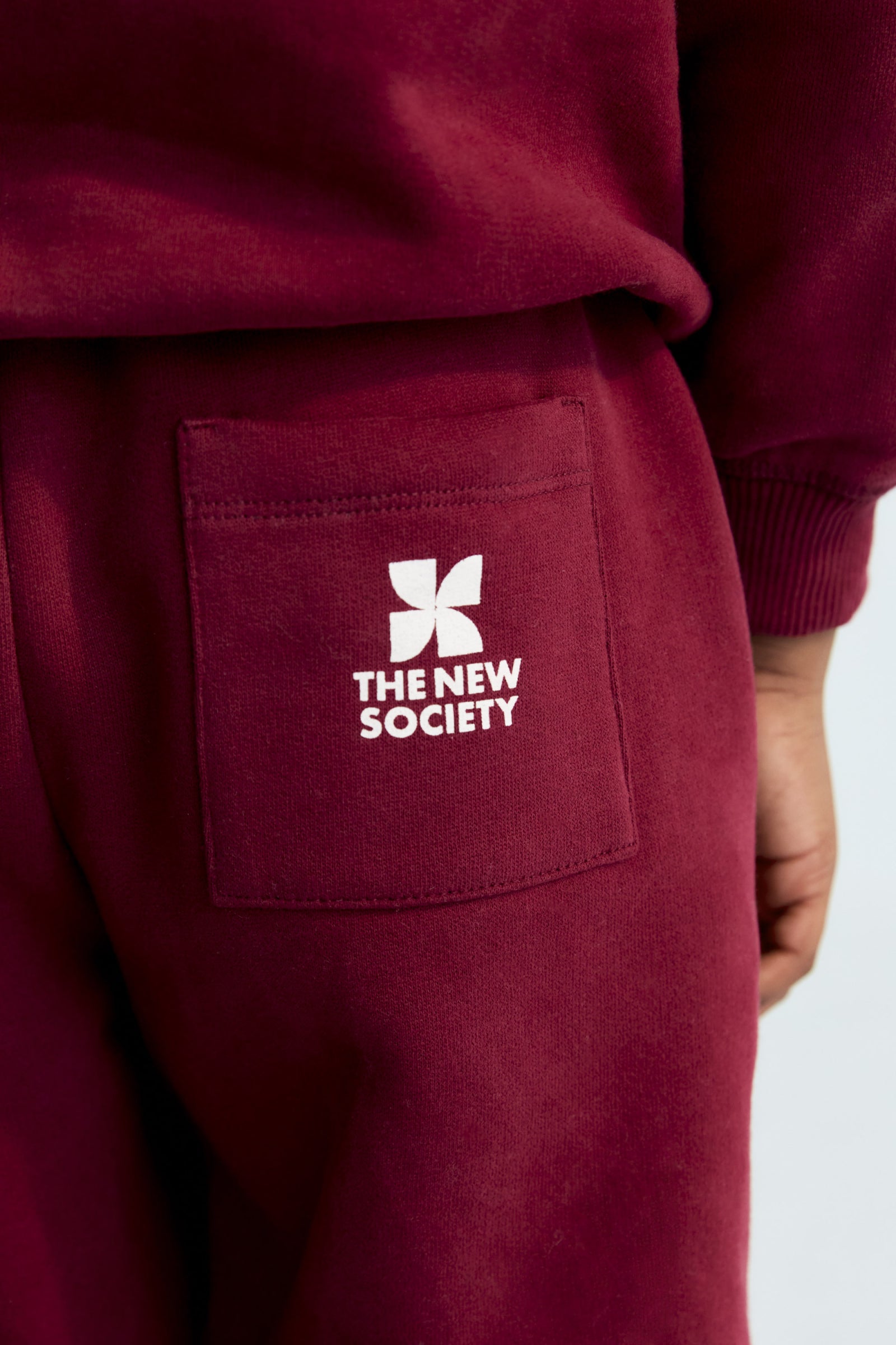 Maroon sweatpants with a logo and text on a white background