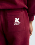 Maroon sweatpants with a logo and text on a white background
