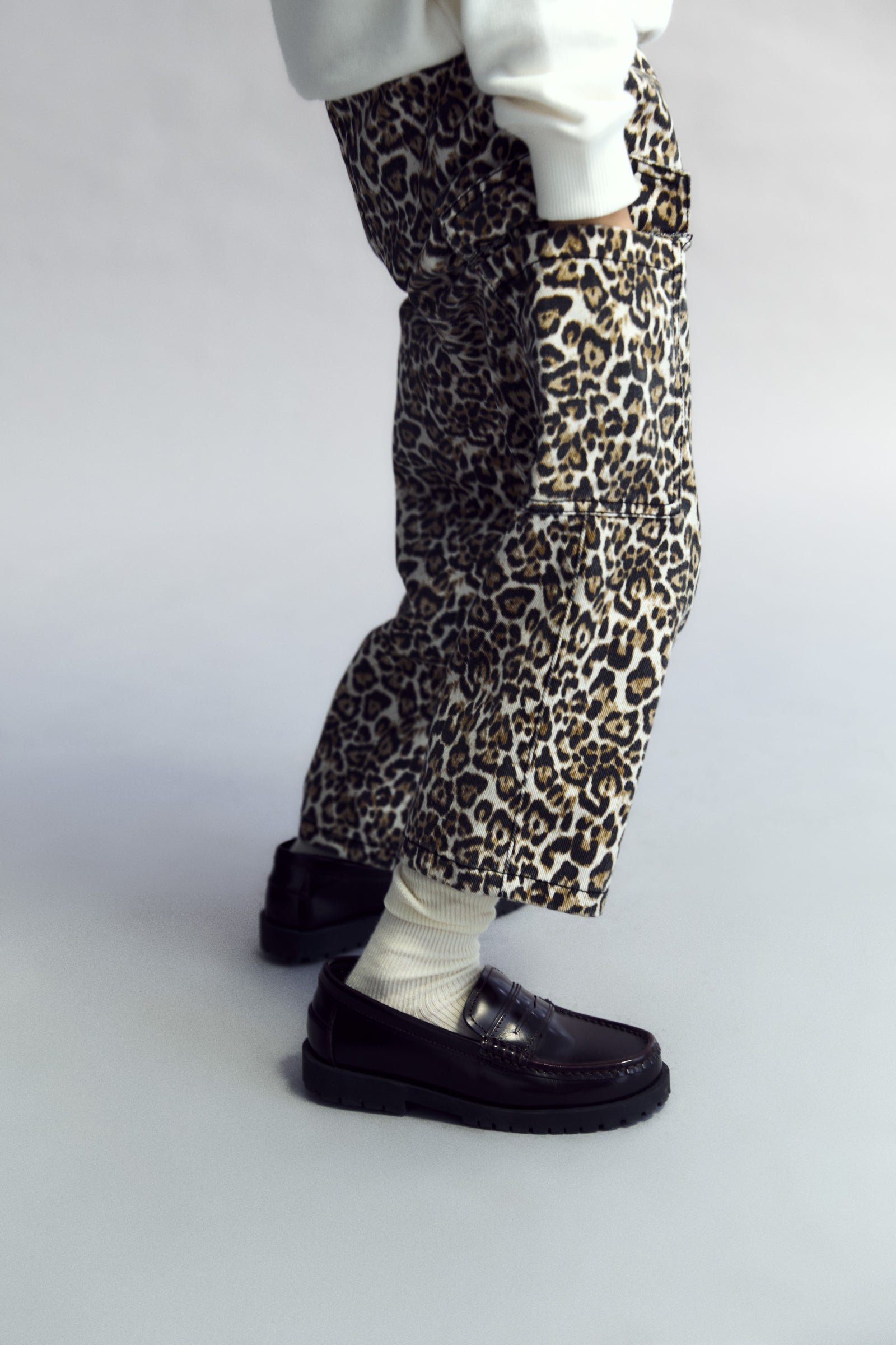 Leopard print pants worn with black shoes on a plain background