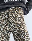 Leopard print pants worn with a dark hoodie on a light background